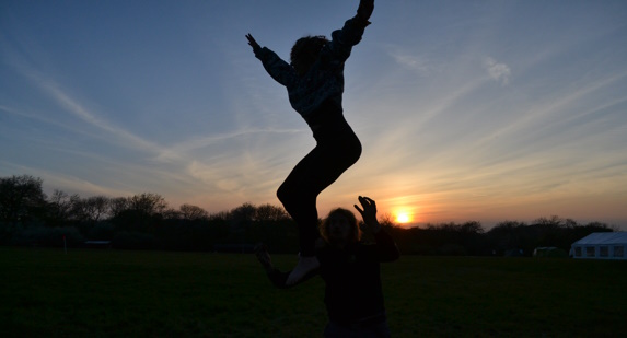 girl being thrown in the air in front of setting sun